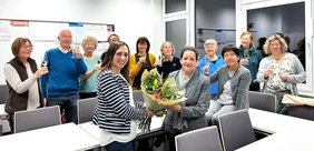 Magali Baudelet überreicht Dozentin Gloria Recalde-Roth einen Blumenstrauß umgeben von ihren Teilnehmenden, Bild: VHS Oldenburg.