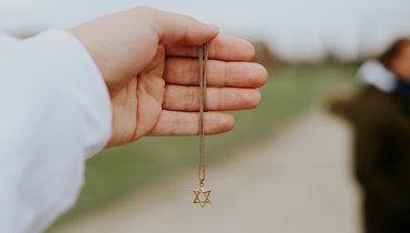 Eine Hand hält eine Kette mit einem David-Stern als Anhänger.