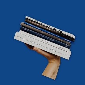 Eine Hand hällt einen Stapel Bücher