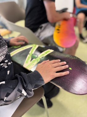 Eine Hand, die ein bemaltes Skateboard festhält