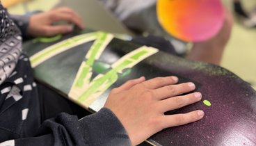 Eine Hand, die ein bemaltes Skateboard festhält